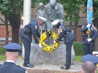 two police officers putting wreath on statue